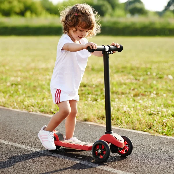 Bella ragazza equitazione scooter allo stadio — Foto Stock