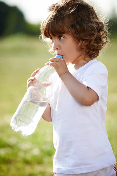 Klein meisje schoon drinkwater uit fles Stockafbeelding