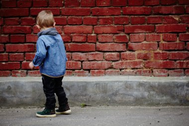 kırmızı tuğla duvar yakınındaki küçük çocuk