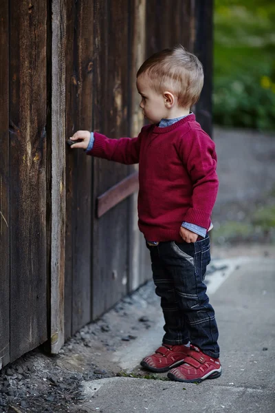 小さな男の子は古いドアを開こうとします。 — ストック写真