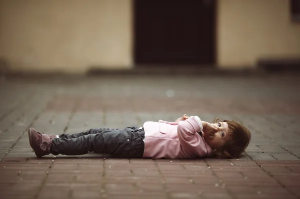 Sevimli küçük kız asfalt üzerinde yalan — Stok fotoğraf