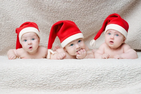 Bebês com chapéus de Papai Noel em fundo brilhante — Fotografia de Stock