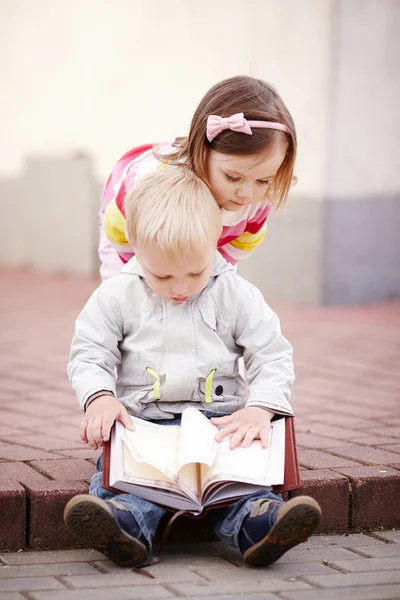 Niño y niña leyendo un libro — Foto de Stock