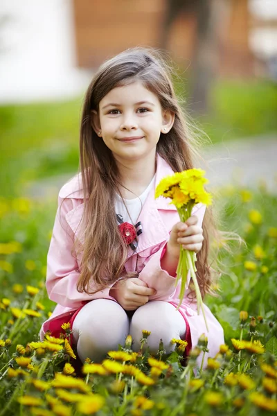 Flicka sitter i fält av blommor — Stockfoto