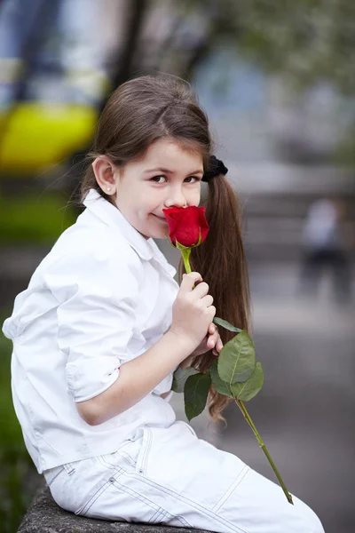 Pretty girl smell rose outdoor in white suit — Stock Photo, Image