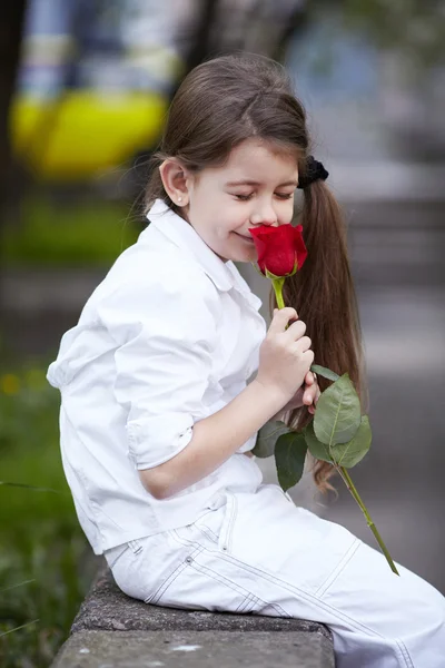 Pretty girl smell rose outdoor in white suit — Stock Photo, Image