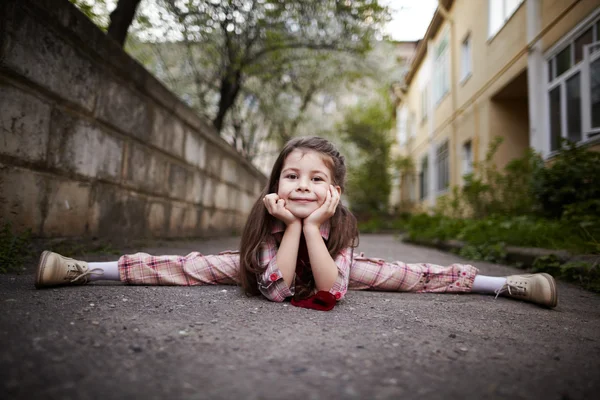 Маленькая симпатичная девочка делает шпагат на открытом воздухе — стоковое фото