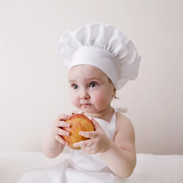 Little cook eats an apple — Stock Photo, Image