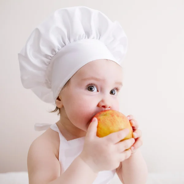 Little cook eats an apple — Stock Photo, Image