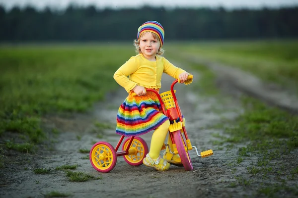 自転車に乗ってカラフルなドレスの女の子 — ストック写真