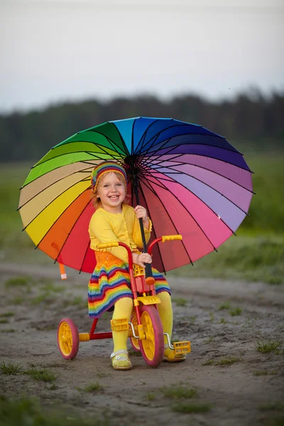 Schattig meisje op de fiets met paraplu in haar handen — Stockfoto