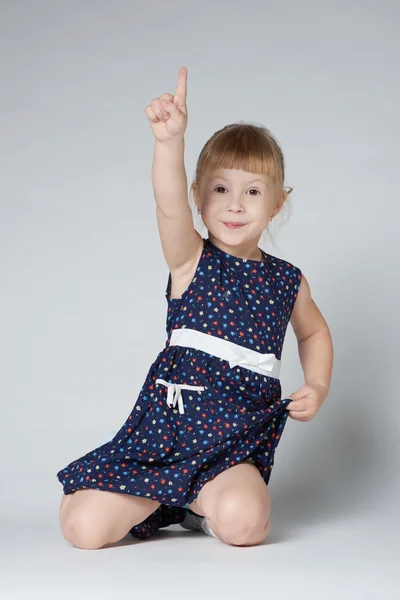 Girl sitting on the floor pointing up — Stock Photo, Image