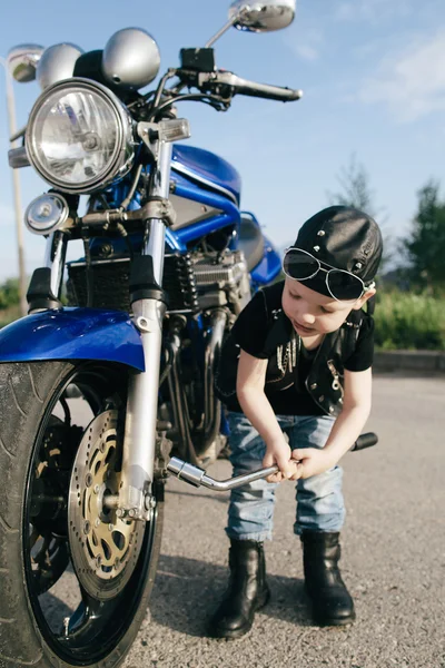 Little biker repairs motorcycle on road — Stock Photo, Image