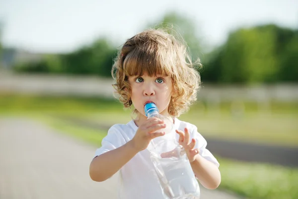 Маленькая девочка пьет чистую воду из пластиковой бутылки — стоковое фото