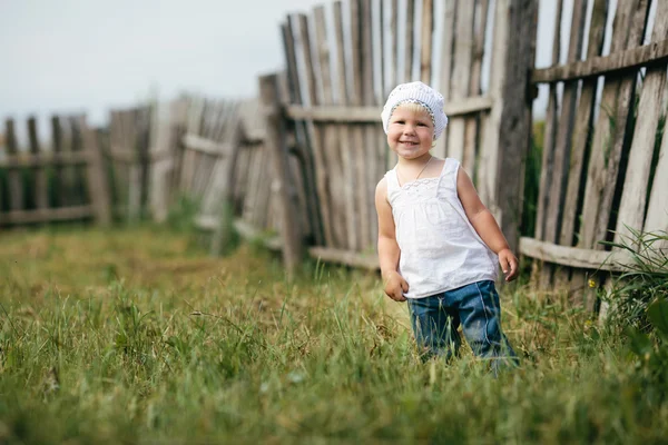 Маленькая девочка и деревянный забор — стоковое фото