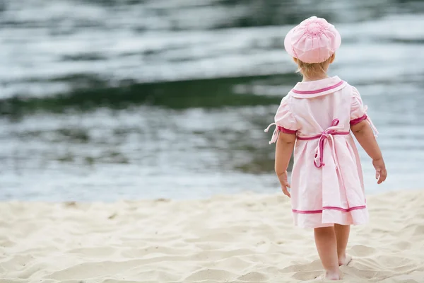 Little girl standing on the coast of river — Stock Photo, Image