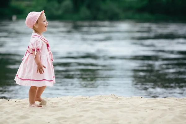 Little girl standing on the coast of river — Stock Photo, Image