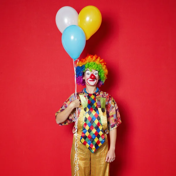 Clown with balloons on red background — Stock Photo, Image