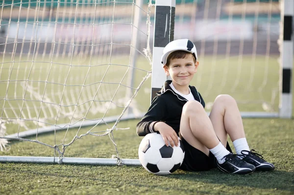 Menino joga futebol no estádio — Fotografia de Stock