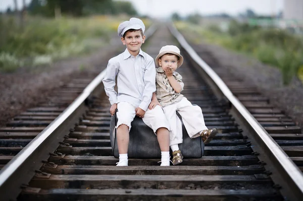 Два мальчика с чемоданом на железной дороге — стоковое фото