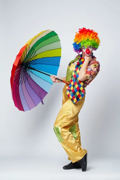 Clown mit buntem Regenschirm auf weiß — Stockfoto