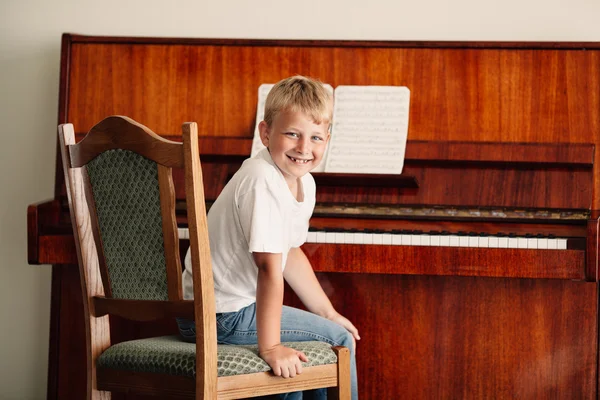 Liten glad pojke spelar piano — Stockfoto