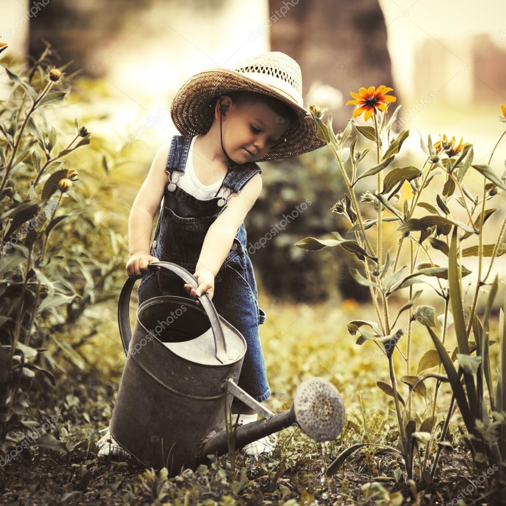 Little boy with watering can in summer park Stock Photo by ©ababaka 79718322
