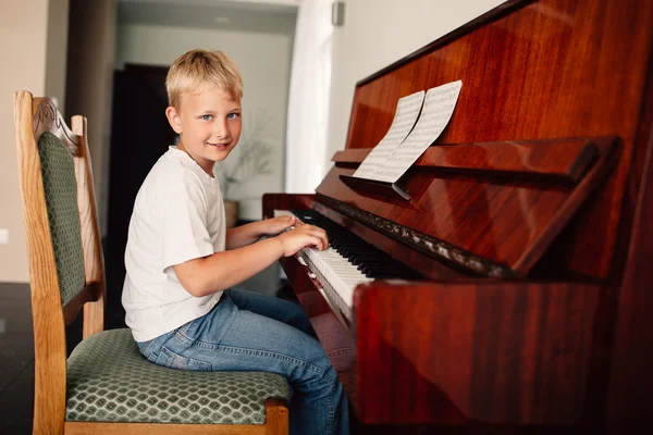 Маленький счастливый мальчик играет на пианино — стоковое фото