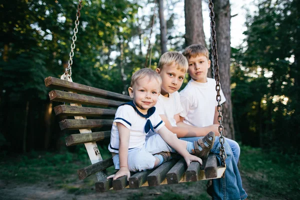 Tre bröder sitter på swing — Stockfoto