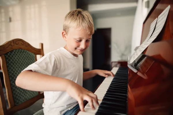 Liten glad pojke spelar piano — Stockfoto