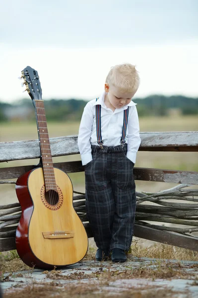 Маленький мальчик с гитарой на месте — стоковое фото