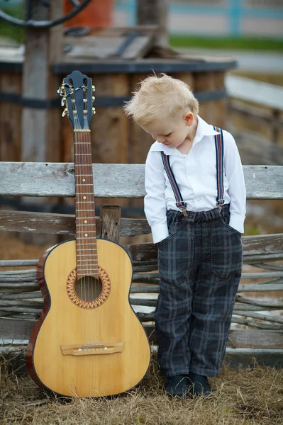 Kleiner Junge mit Gitarre vor Ort — Stockfoto