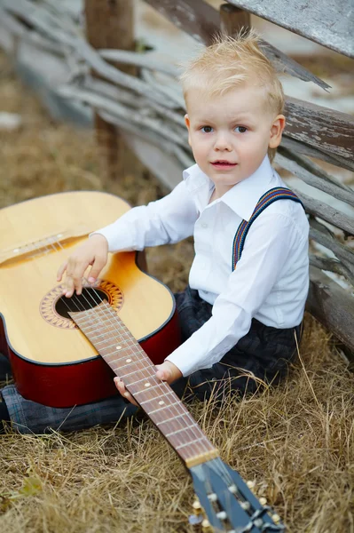 Kleiner Junge mit Gitarre vor Ort — Stockfoto