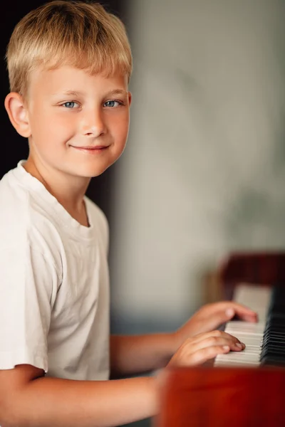 Liten glad pojke spelar piano — Stockfoto