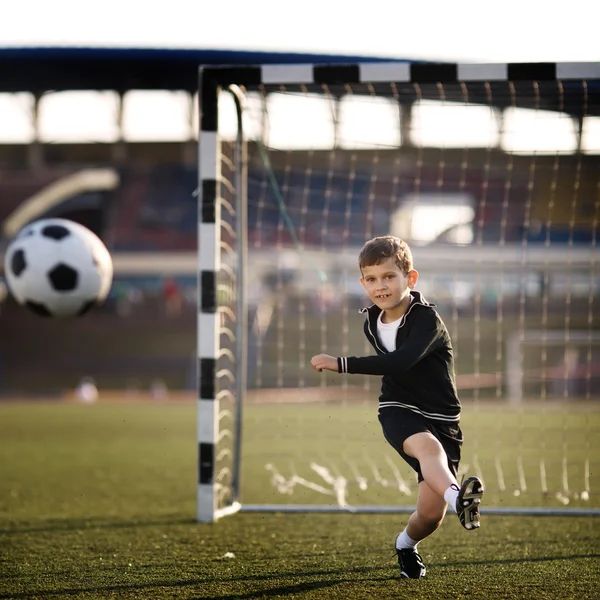 Мальчик играет в футбол на стадионе — стоковое фото