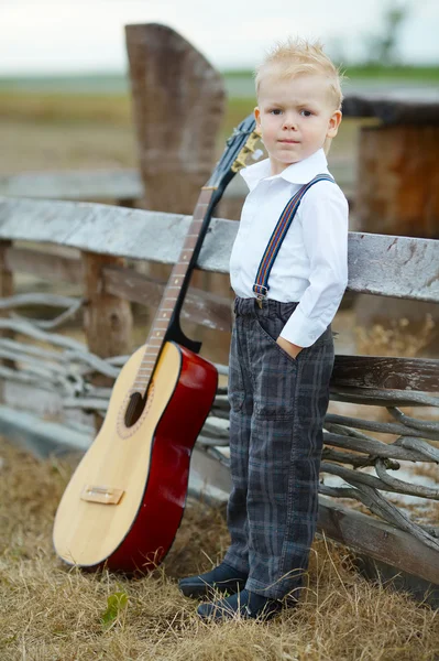 Malý chlapec s kytarou na místě — Stock fotografie