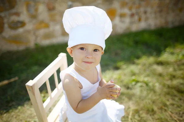 Niño con chefs sombrero come manzana —  Fotos de Stock