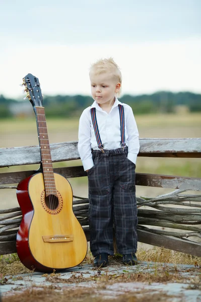 Kleine jongen met gitaar op locatie — Stockfoto