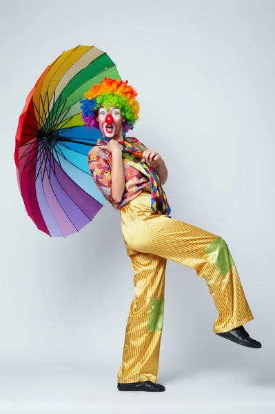 Clown mit buntem Regenschirm auf weiß — Stockfoto