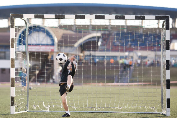 boy plays football on stadium