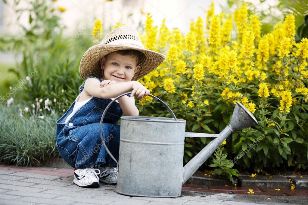 Little boy with watering can in summer park Stock Photo by ©ababaka