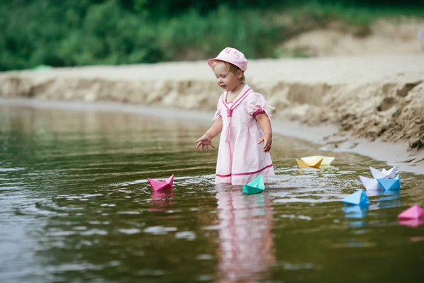 Fille joue avec des bateaux en papier dans la rivière — Photo