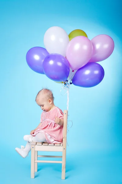 Kleines Mädchen mit Luftballons auf blauem Hintergrund — Stockfoto