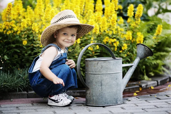 Маленький мальчик с лейкой в летнем парке — стоковое фото
