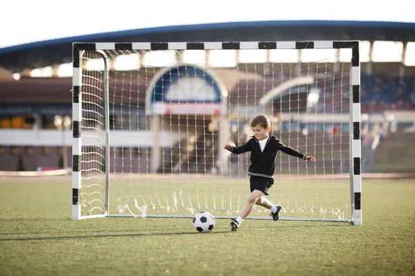 Мальчик играет в футбол на стадионе — стоковое фото
