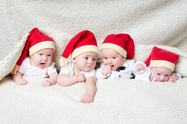 Bebês com chapéus de Papai Noel em fundo brilhante — Fotografia de Stock