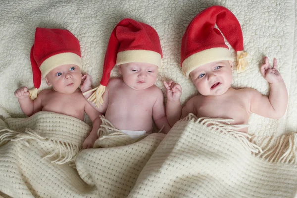 Bebês com chapéus de Papai Noel em fundo brilhante — Fotografia de Stock