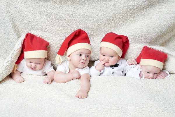 Babys mit Weihnachtsmützen auf hellem Hintergrund — Stockfoto