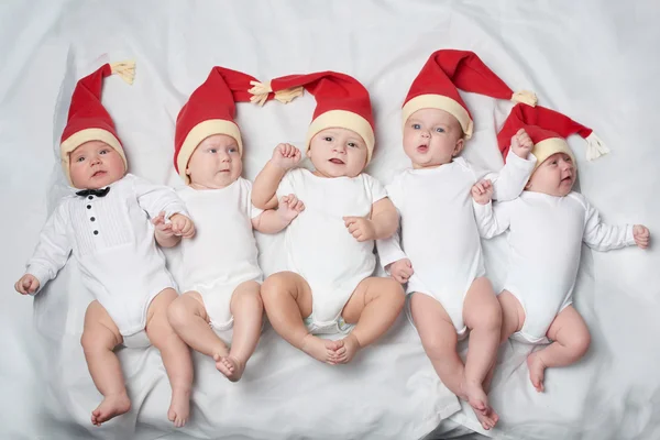 Babys mit Weihnachtsmützen auf hellem Hintergrund — Stockfoto
