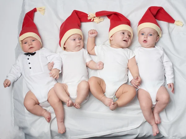 Bebês com chapéus de Papai Noel em fundo brilhante — Fotografia de Stock